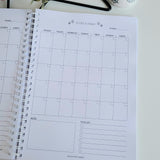 Christmas Planner on a white surface with decorative items in the background