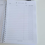 Christmas Notebook with a gift list for children on a white surface with decorative items.