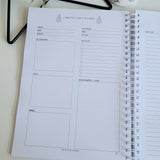 Christmas Party planner on a white surface with decorative items in the background