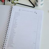 Open notebook with Christmas planner contents-christmas themed decorations on a white surface